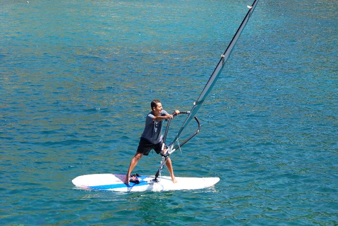 man in black shirt and black shorts riding white surfboard on blue sea during daytime